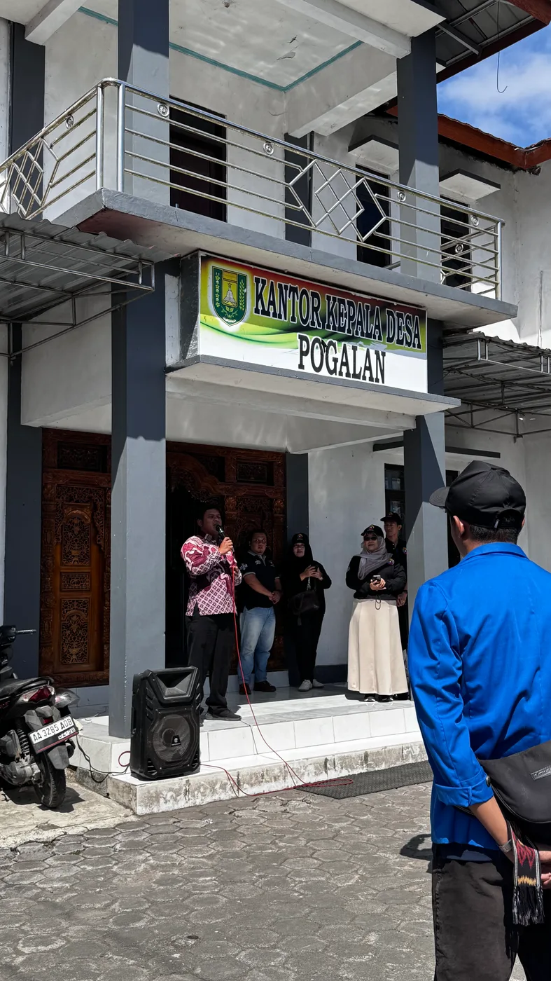 Perangkat desa dan mahasiswa berdiri di depan pintu Kantor Kepala Desa Pogalan saat penyambutan