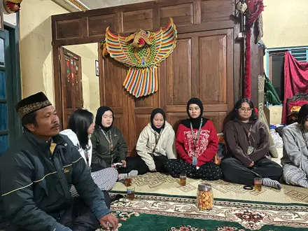Mahasiswa dan warga duduk melingkar di ruang tamu untuk berbincang bersama