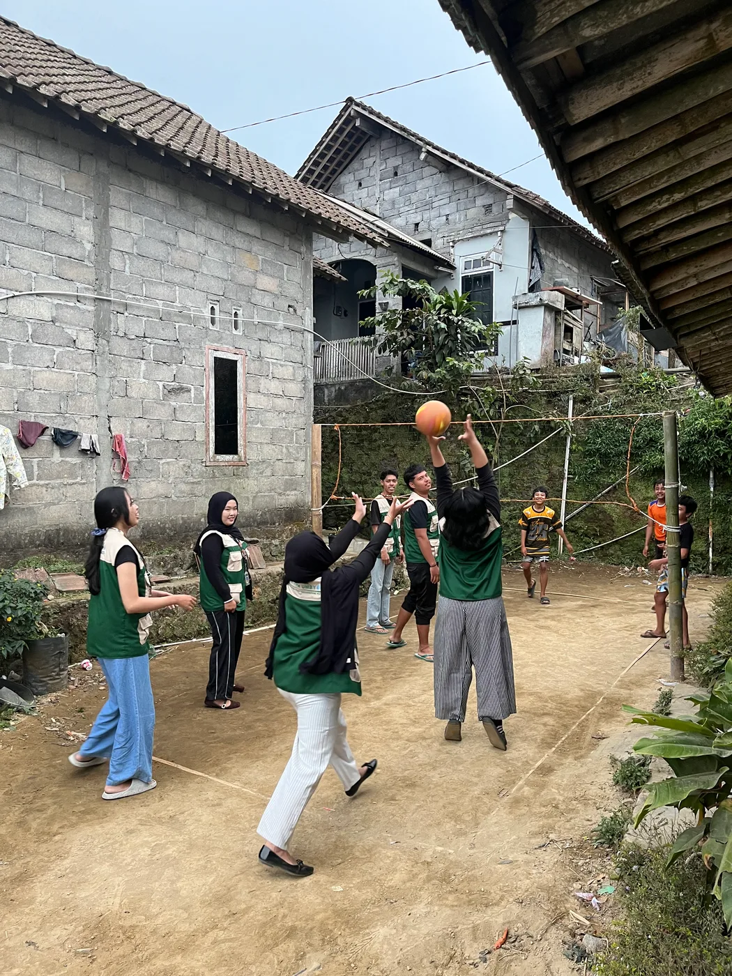 Mahasiswa dan warga bermain bola voli di lapangan kecil di antara rumah