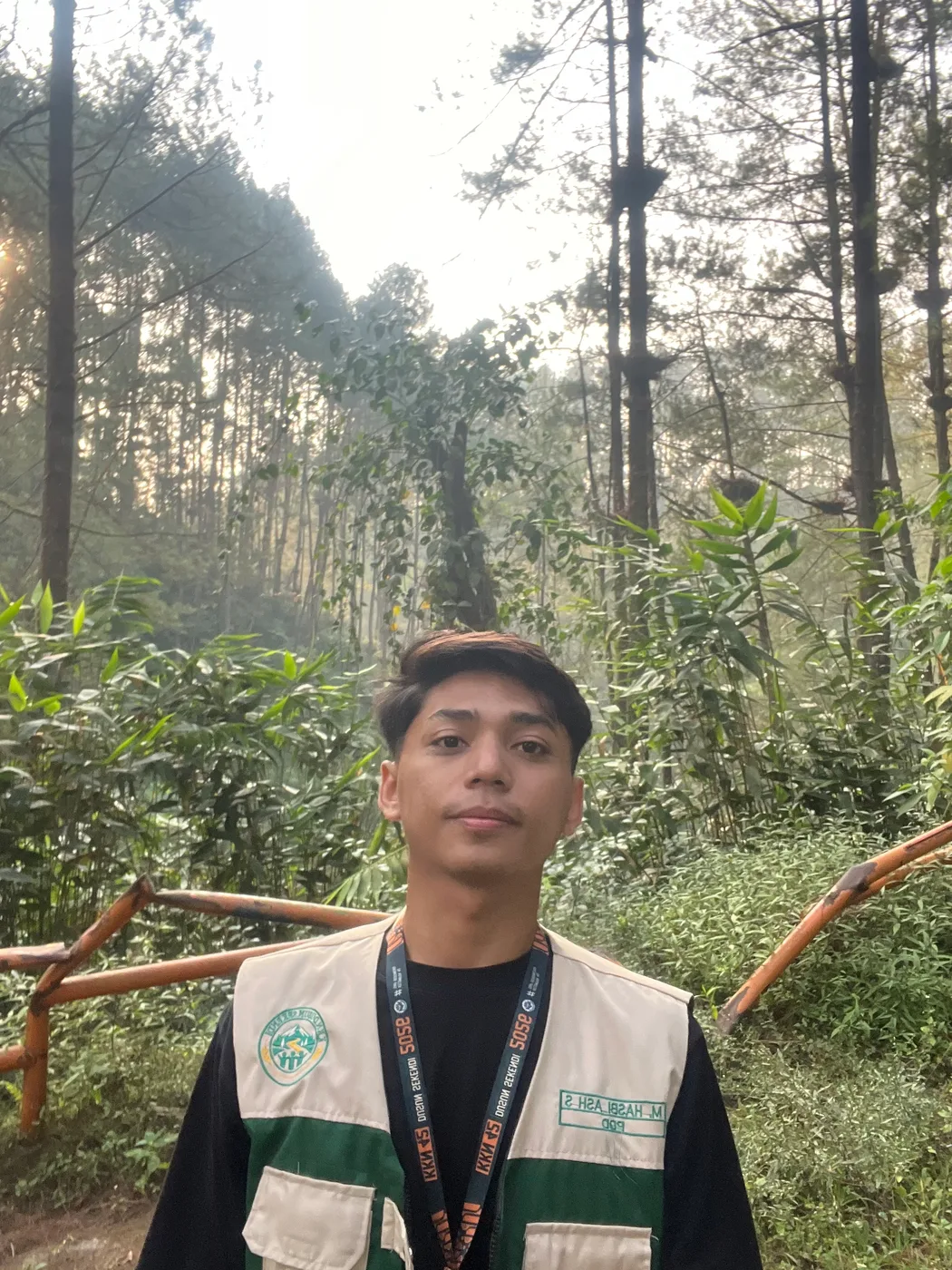 Seorang anggota kelompok berselfie dengan pepohonan dan jalan setapak di belakangnya