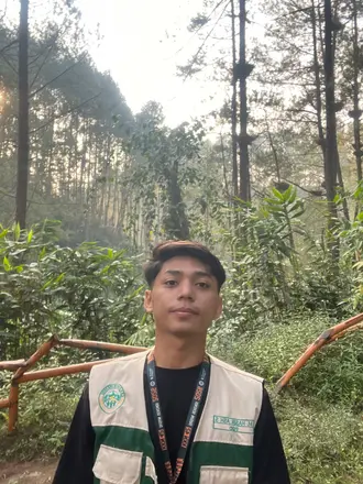 Seorang anggota kelompok berselfie dengan pepohonan dan jalan setapak di belakangnya