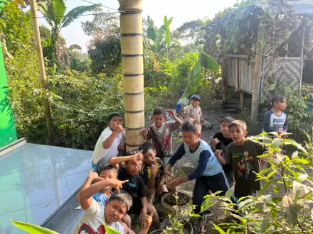 Mahasiswa dan anak-anak berfoto ramai-ramai di depan teras rumah